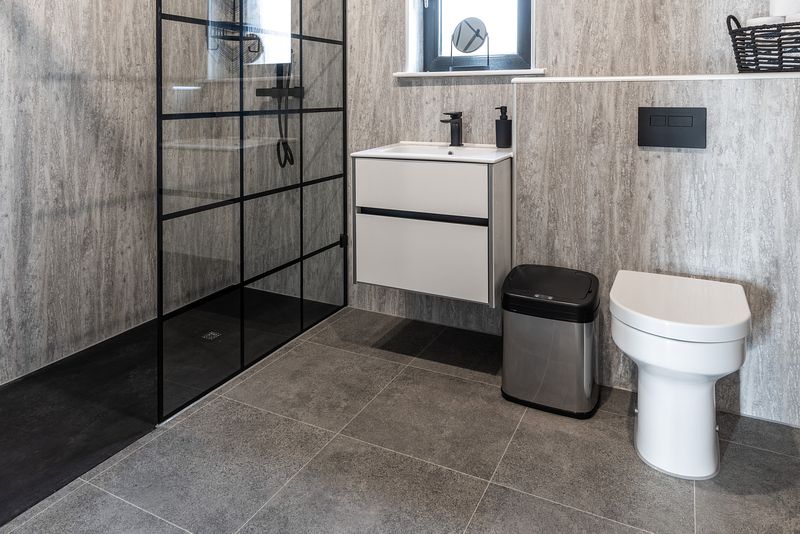 A clean and modern shower room with angular lines, featuring toilet, sink and walk in shower