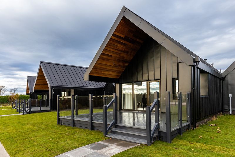 The chalets are sitting on the short green grass, with their modern black clad exteriors.