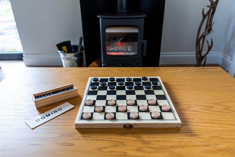 Dominoes and checkers open on a table in front of a fire